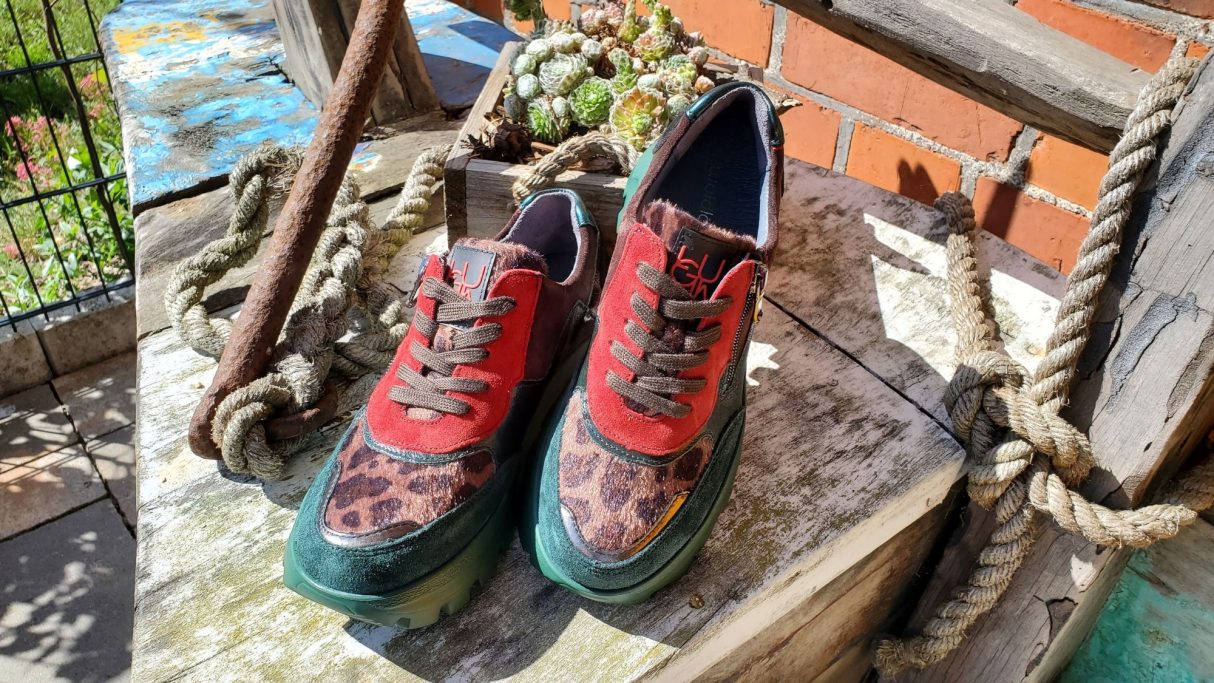 Bunte Sneaker mit Leopardenmuster auf einer Holzoberfläche.