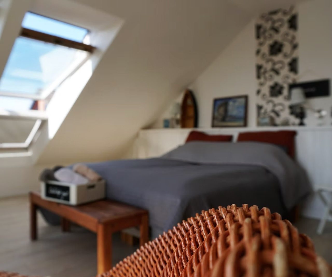 Geminstein Schlafzimmer mit Dachfenster, Bett und gemütlichem Holzstuhl.