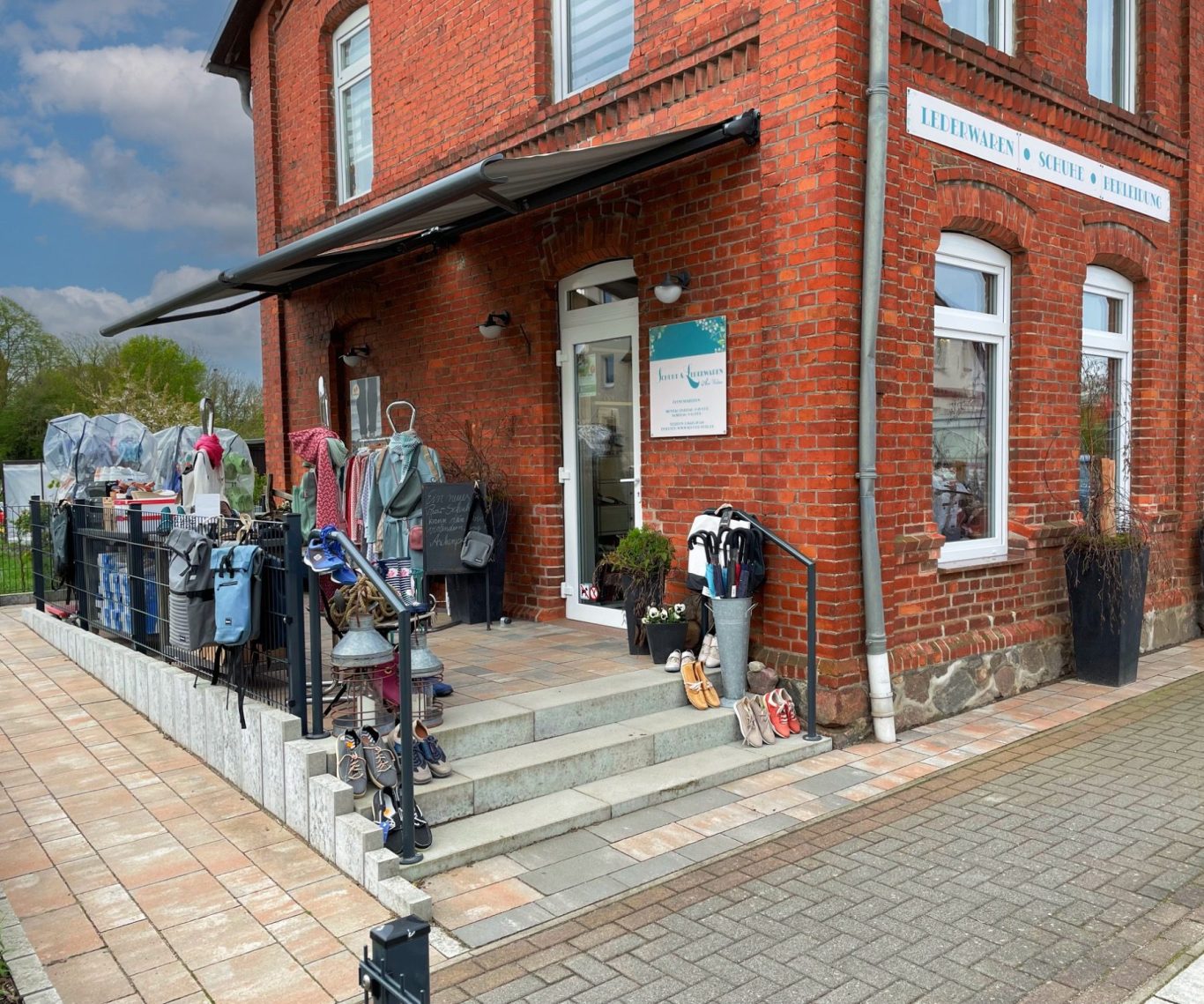 Eingang zu einem roten Ziegelgebäude mit Kleidung und Accessoires im Freien.