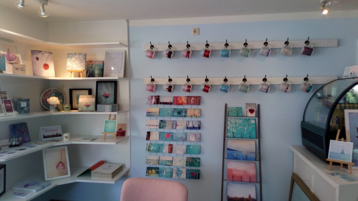 Helle, einladende Boutique mit bunten Karten und Accessoires auf Regalen.