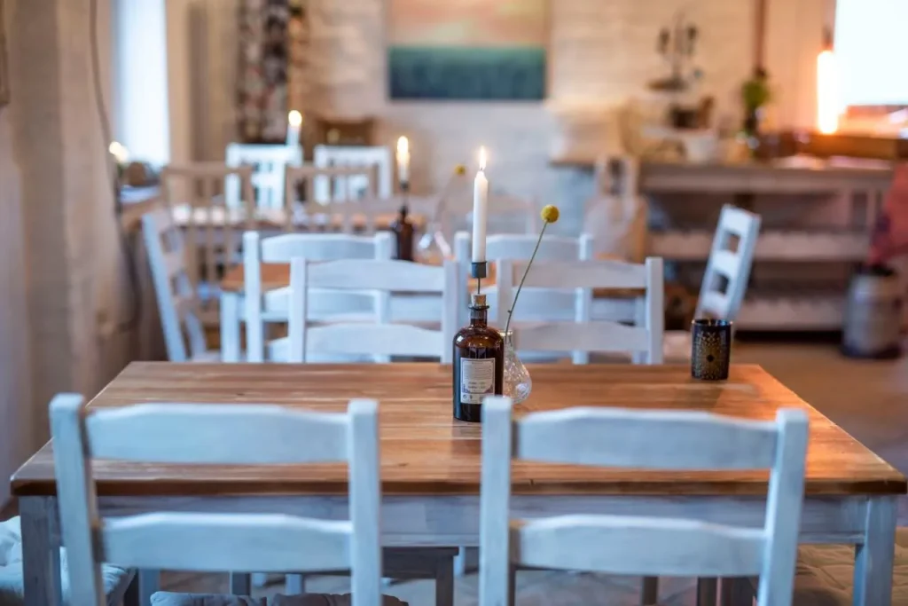 Holztisch mit weißen Stühlen und dekorativen Flaschen in einem einladenden Restaurant.