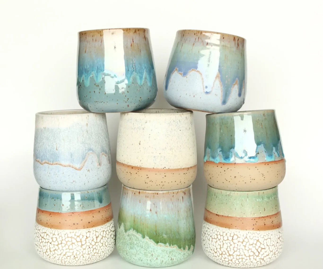 Bunte Keramiktassen in verschiedenen Farben und Glasuren, gestapelt.