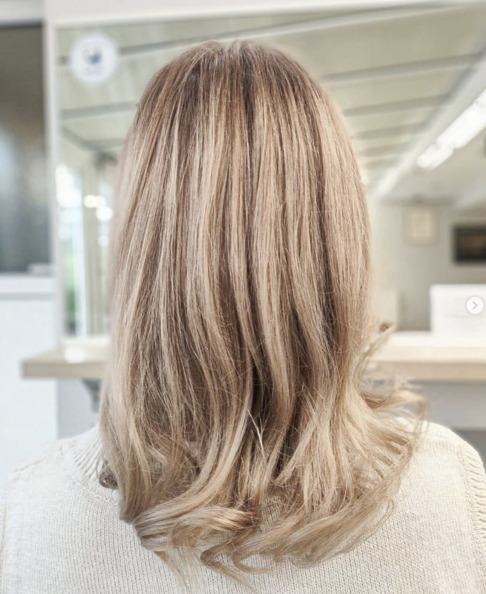 Heller, schulterlanger Haarschnitt mit sanften Wellen und blondem Farbverlauf.