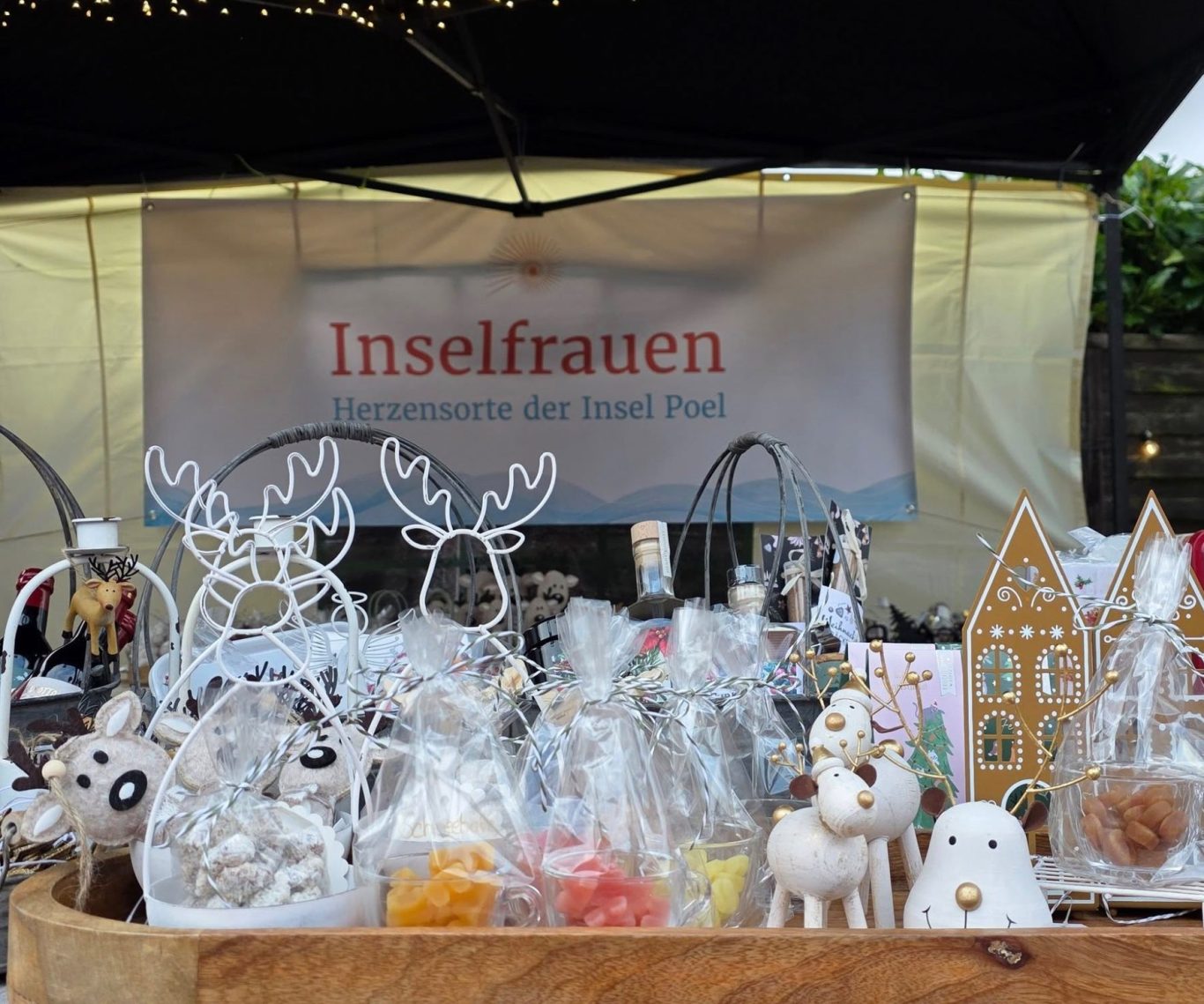 Handgefertigte Figuren und Dekorationen auf einem Marktstand vor einem Banner.
