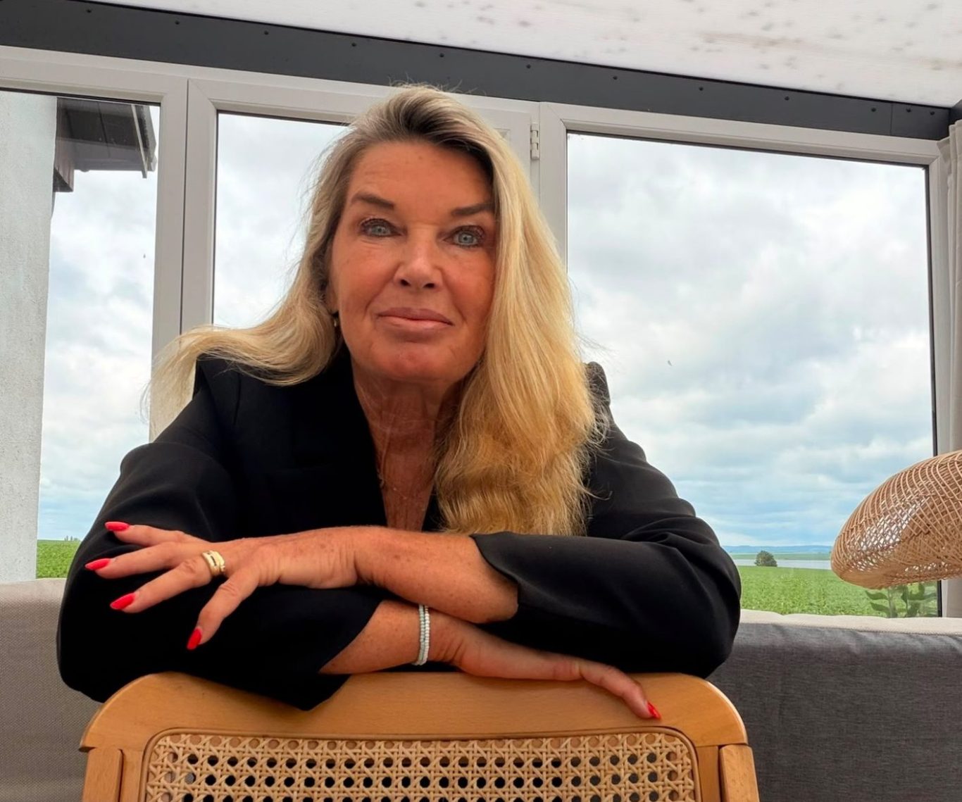 Frau mit blonder Haarfarbe in rosa Bluse sitzt auf Treppe.