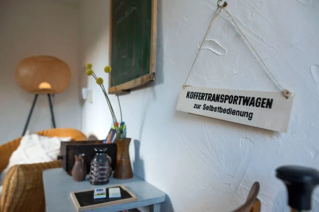 Gemütliche Ecke mit Deco-Elementen, Tisch und Pflanzen, beschriftetes Schild im Hintergrund.