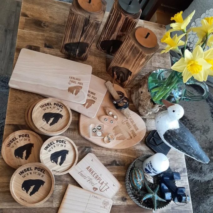 Holzuntersetzer, Kerzen, dekorative Objekte und frische Blumen auf einem Tisch.