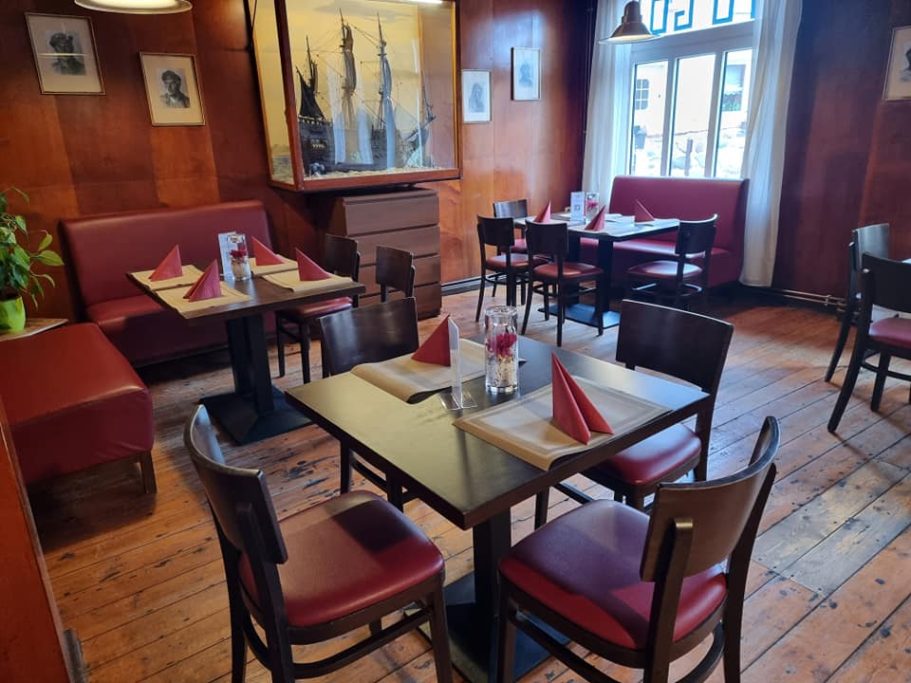 Gemütliches Restaurant mit Holzvertäfelung, Tischen und Roten Sitzplätzen.