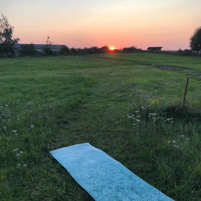 Eine Yoga-Matte liegt auf einer Wiese bei Sonnenuntergang.