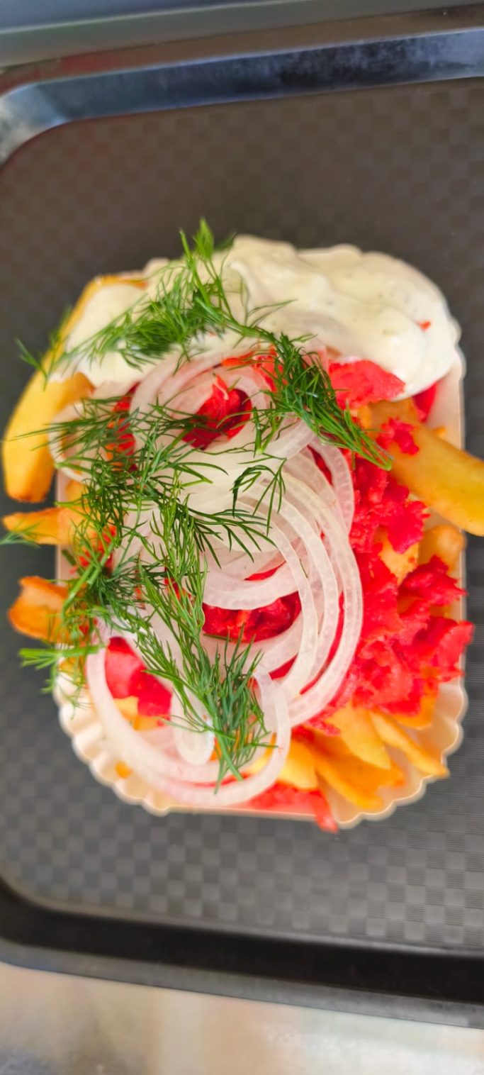 Flaches Brot belegt mit Tomaten, Zwiebeln, Soße und frischen Kräutern.