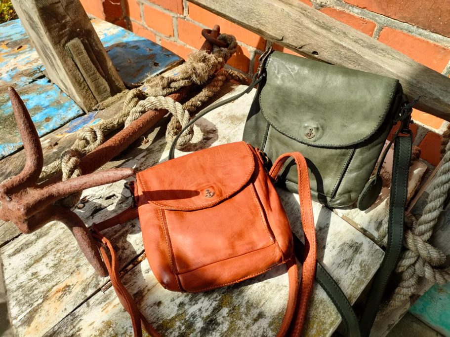 Zwei Taschen, eine orange und eine olivgrün, auf rustikalem Holzuntergrund.