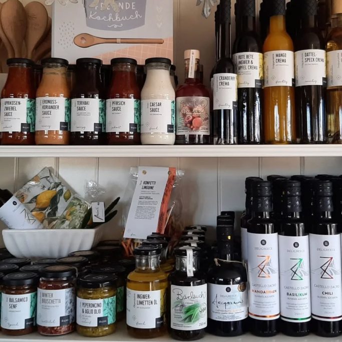 Regal mit verschiedenen Saucen, Marmeladen und Ölen in Gläsern und Flaschen.