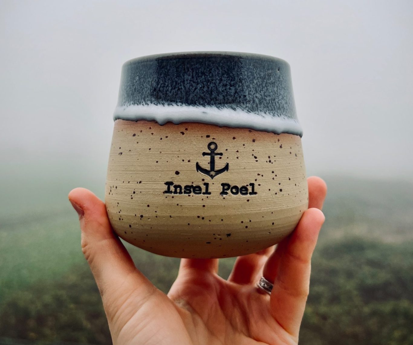 Blauer Kaffeebecher auf einem bunten, herbstlichen Laubhaufen.