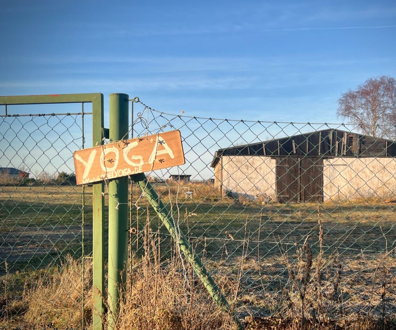 Holzschild mit der Aufschrift „YOGA“ hängt an einer alten, rustikalen Tür.