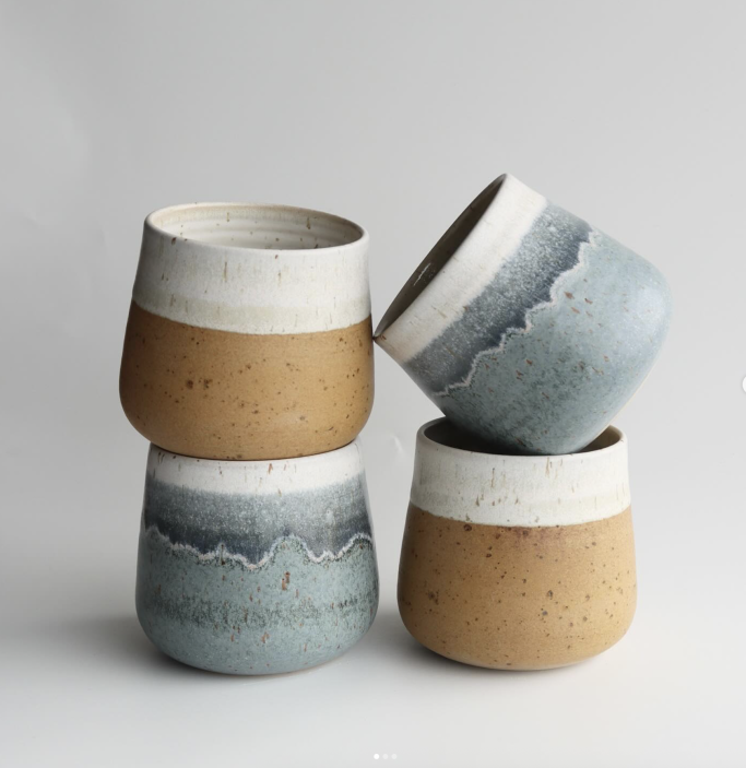 Vierset aus handgefertigten Tontöpfen in blau und braun mit verschiedenen Oberflächendesigns.