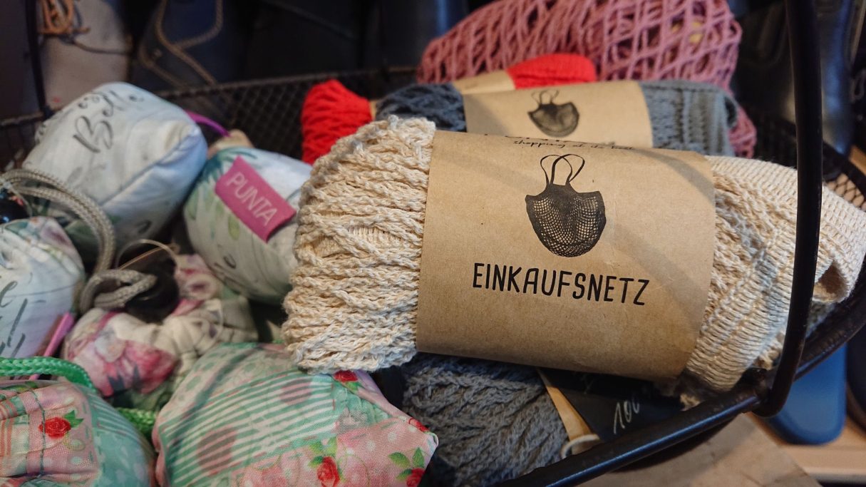 Bunte Wollknäuel und eine Packung mit der Aufschrift "Linkasatz" in einem Korb.