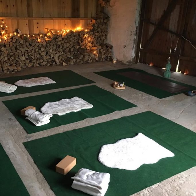 Ruhiger Raum mit grünen Matten, Decken und einigen Yoga-Accessoires.