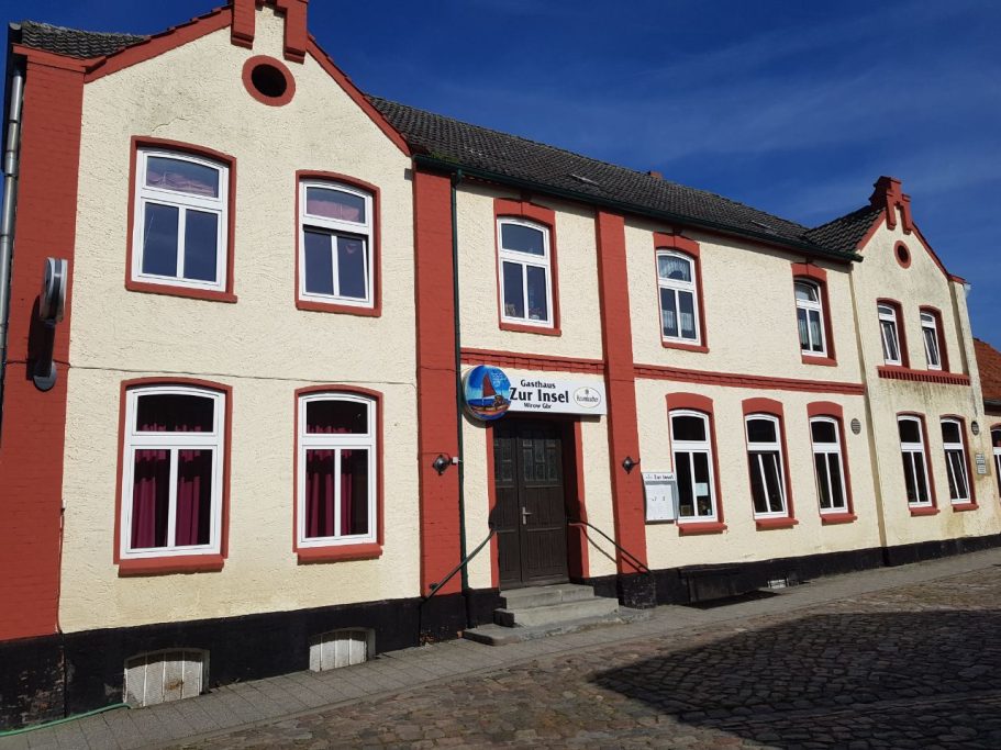 Gelb-rote Fassade eines zweigeschossigen Gebäudes mit mehreren Fenstern.