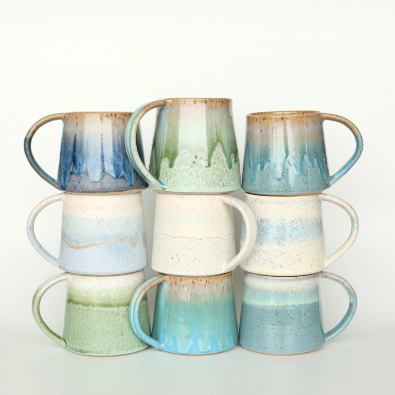 Bunte Keramiktassen mit unterschiedlichen Farbtönen, gestapelt.