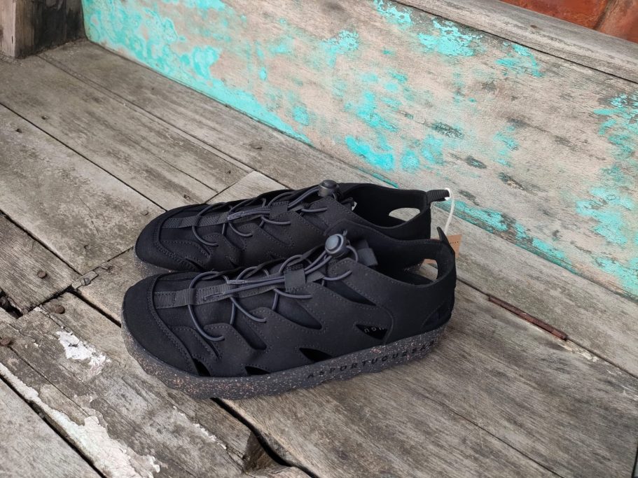 Schwarze Sportschuhe auf einem Holzfußboden mit blauer Farbe.