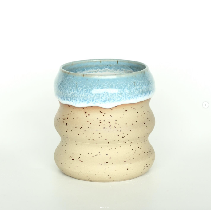 Gestreifter Keramikbecher mit blauer und beige-fleckiger Oberfläche.