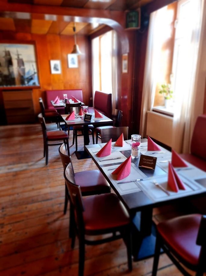 Tisch gedeckt mit roten Servietten in einem gemütlichen Restaurant mit Holzvertäfelung.