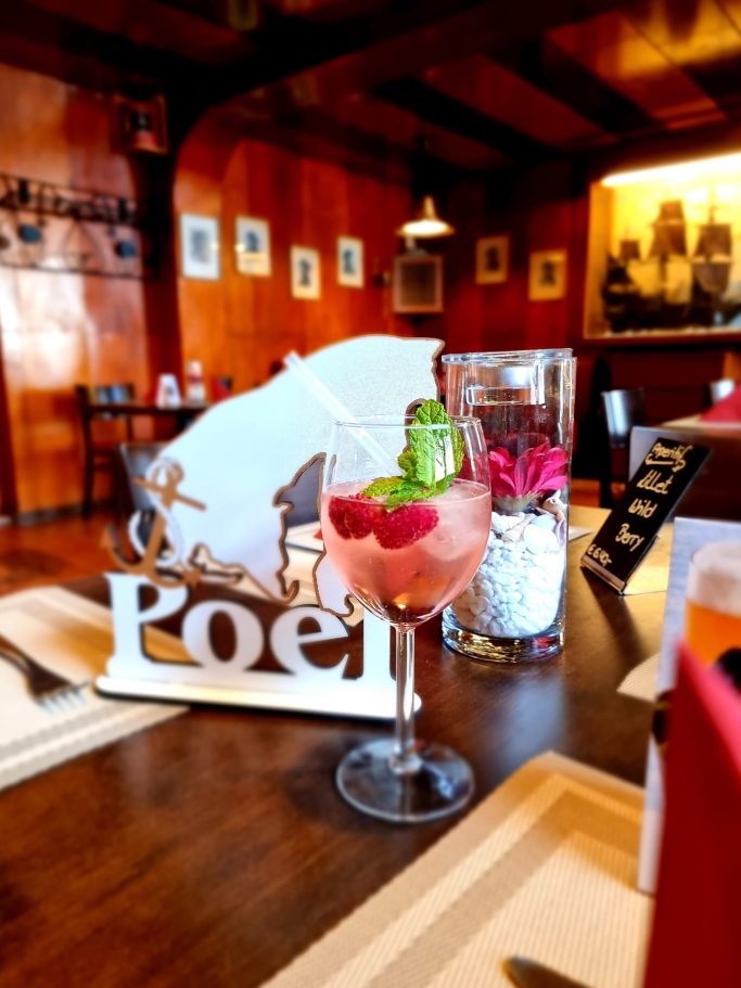 Cocktail mit Himbeeren und Gurken, Tischdekoration in einem gemütlichen Restaurant.